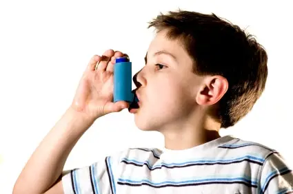 A young boy using an asthma inhaler, with a concerned expression on his face