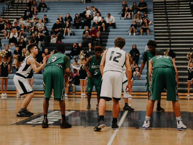 A basketball game in progress, with players from both teams on the court and spectators in the stands