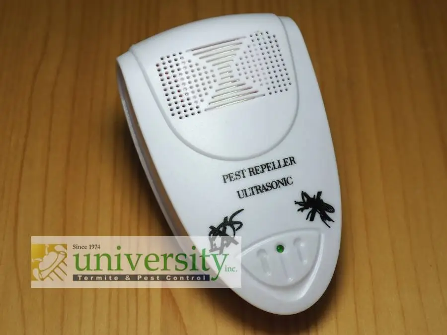 White ultrasonic pest repeller on wooden surface, labeled "Pest Repeller Ultrasonic," with logos for spiders and company branding.