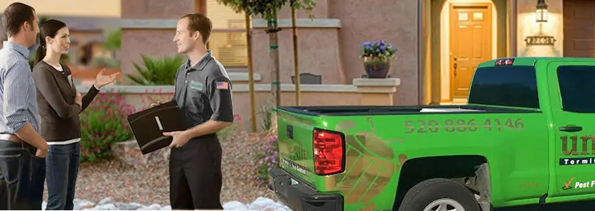 A group of people, including a man and a woman, standing outside near a green commercial vehicle labeled with a company name and phone number.